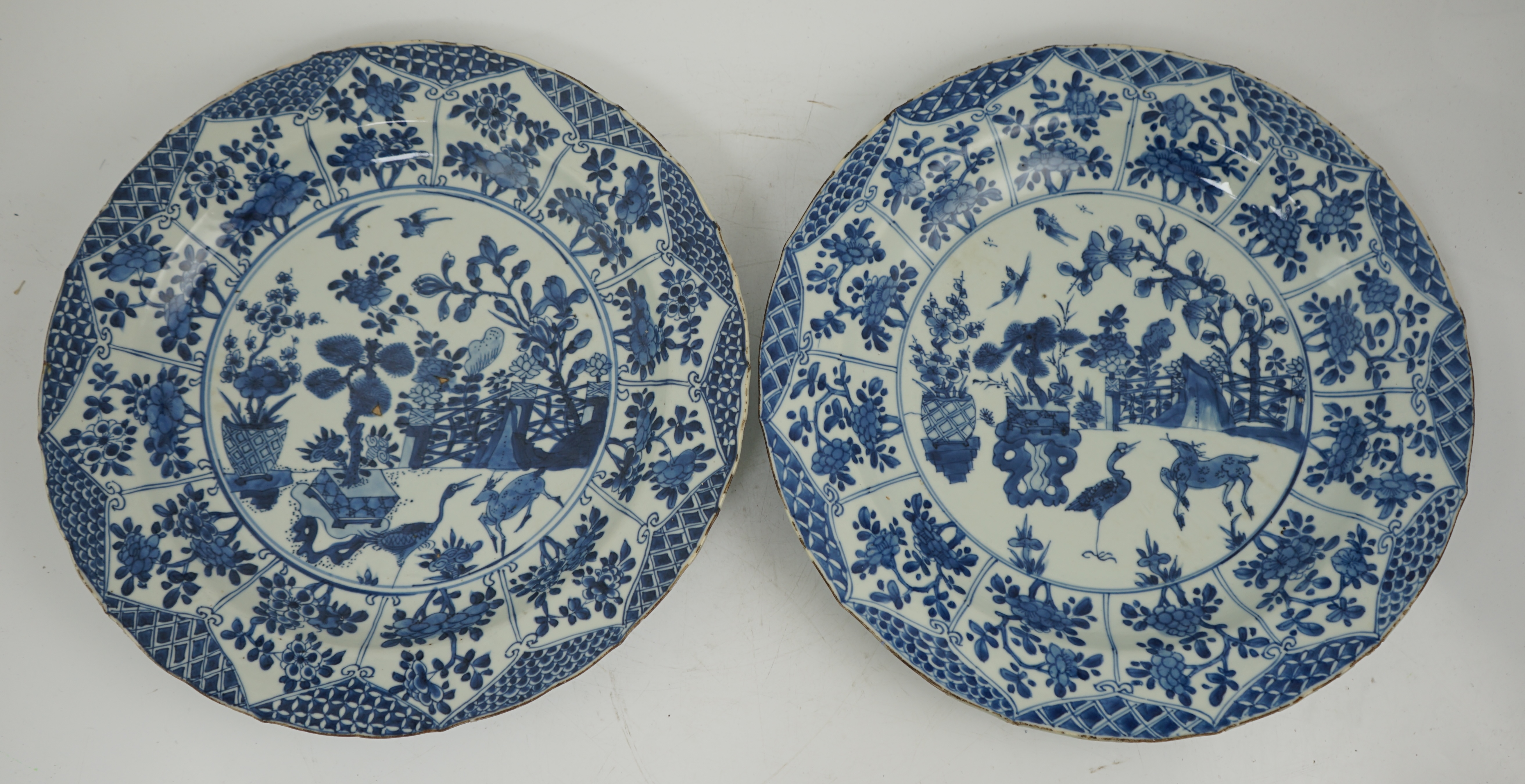 A pair of Chinese blue and white ‘garden’ dishes, Kangxi period, fritting and glaze chips